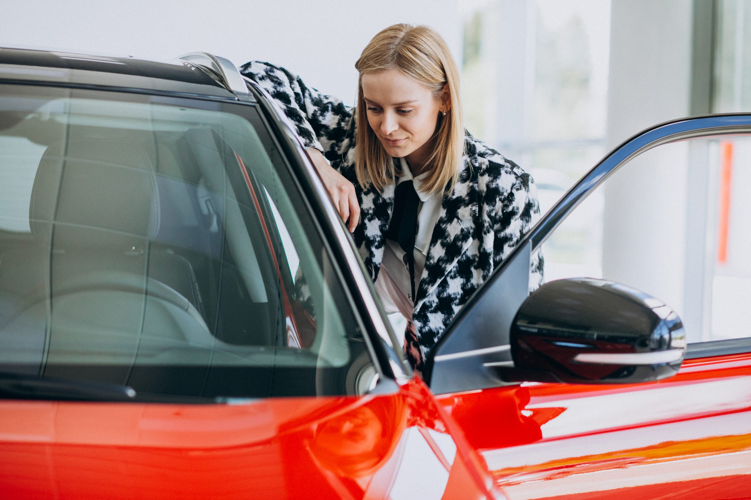 Young woman buying a car in a car showroom skup samochodów
